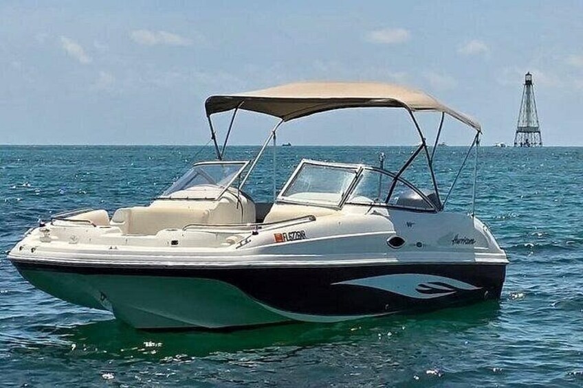 A speedboat with a canopy, white and black color scheme, and a logo on the side. 1