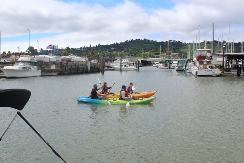 Two kayaks on calm water with a marina and boats in the background. 1