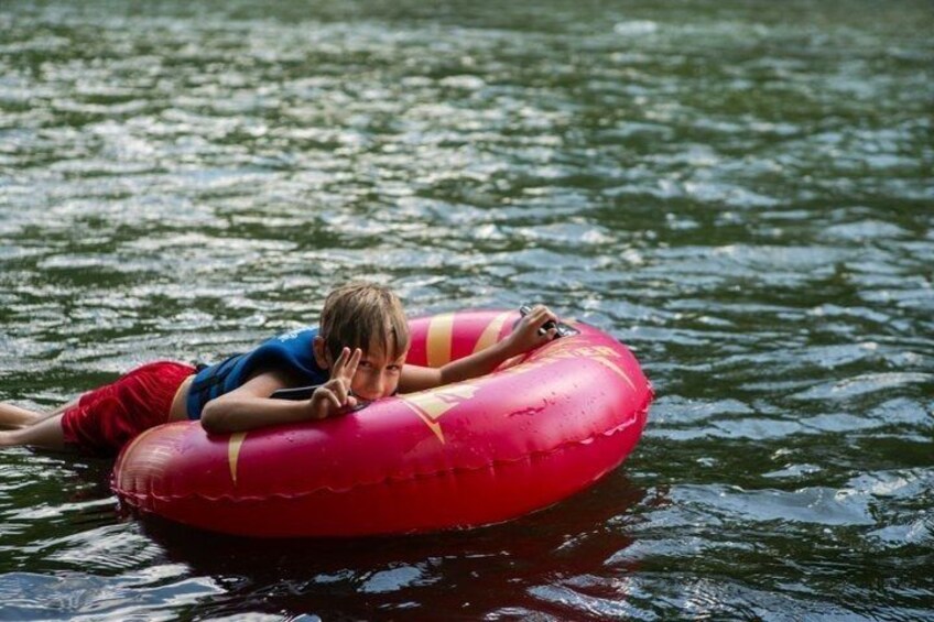 A person floating on a red inflatable tube in a body of water. 4