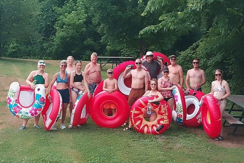 A group of people holding inflatable rings in a grassy area with trees in the background. 1