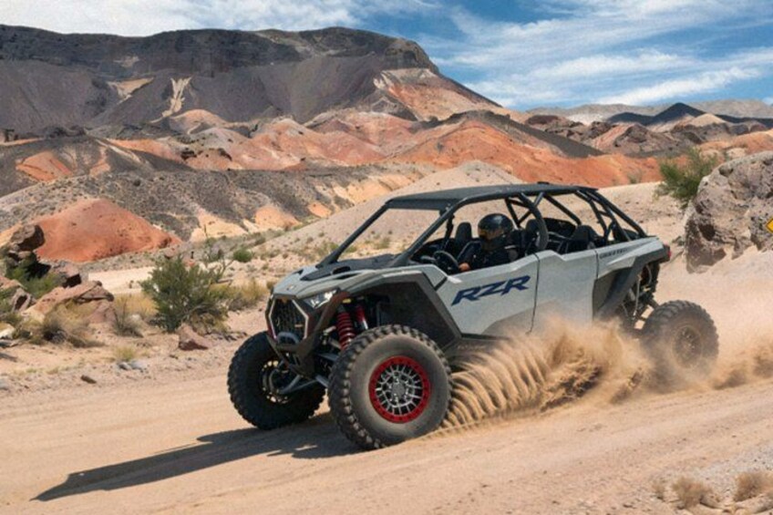 A RZR off-road vehicle driving on a dirt road with a desert landscape in the background. 5