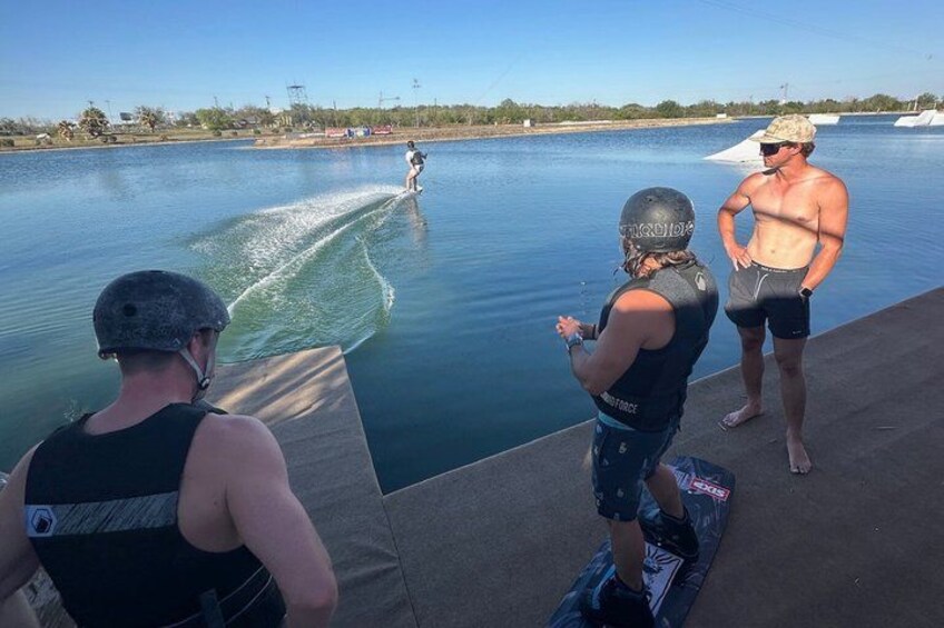 A wakeboarding activity on a calm water body with onlookers. 4