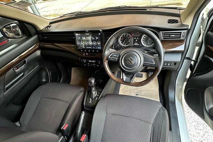 A car's interior with a steering wheel, dashboard, and gear shift. 5