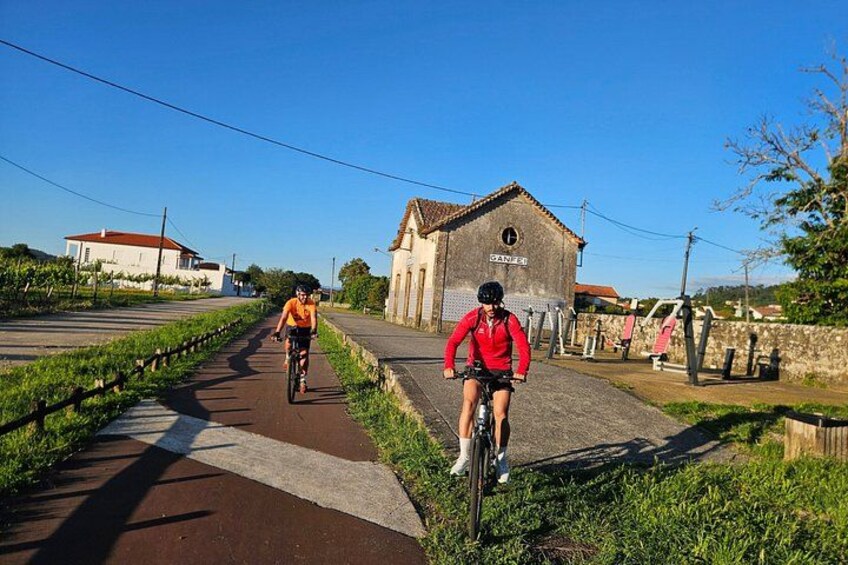 Two cyclists on a paved path with a building labeled 'SANFEL' in the background. 4