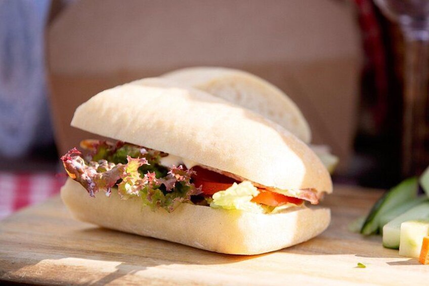 A sandwich on a wooden surface with lettuce, tomato, and other ingredients visible. 2