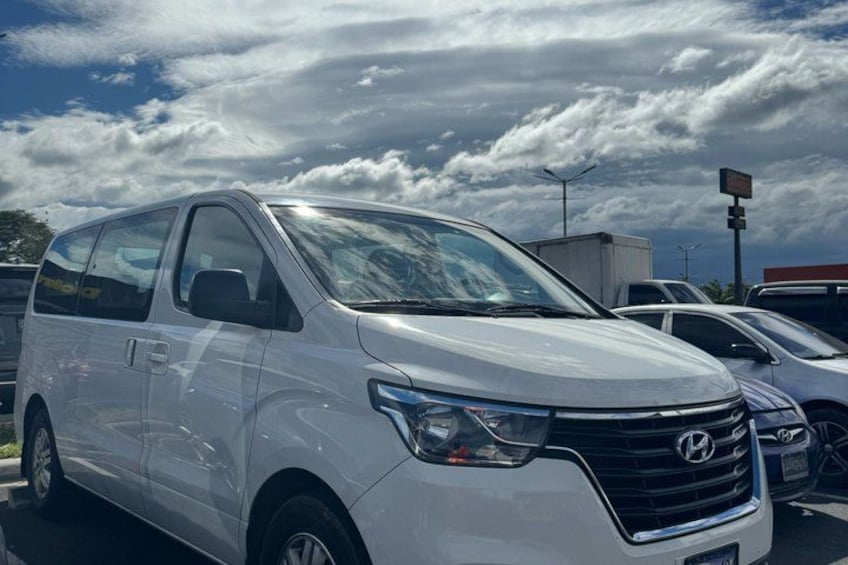 A white van parked in a lot with a cloudy sky in the background. 1