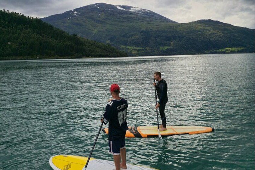 Two people paddleboarding on a lake with mountains in the background. 3
