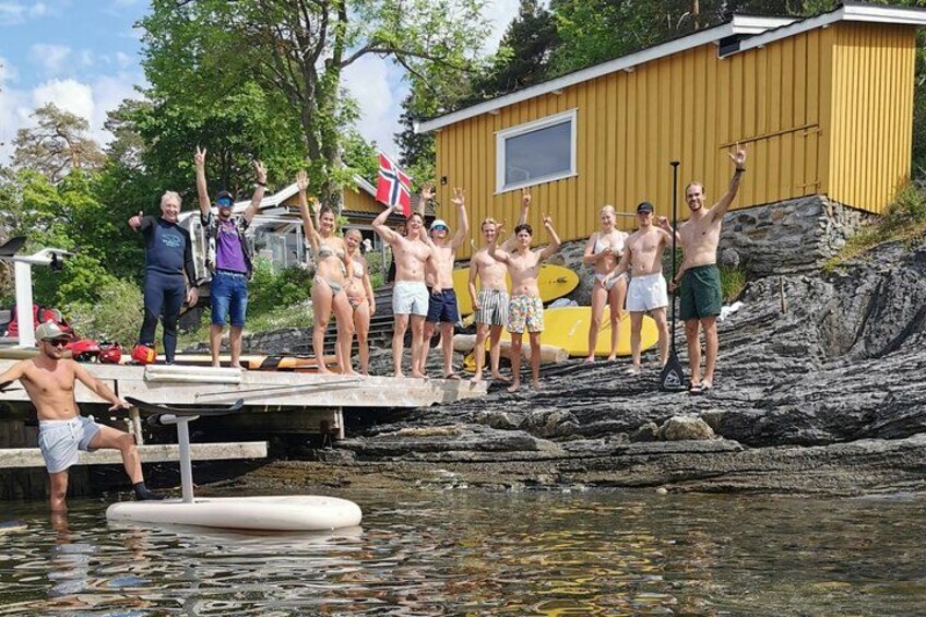 A group of people on a rocky shore with a yellow building in the background. 1