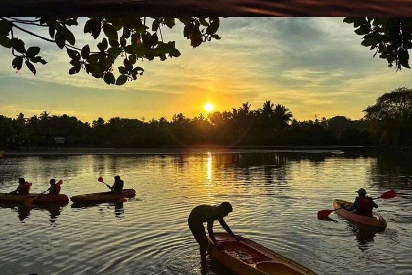 A sunset over a calm lake with people paddling kayaks. 3