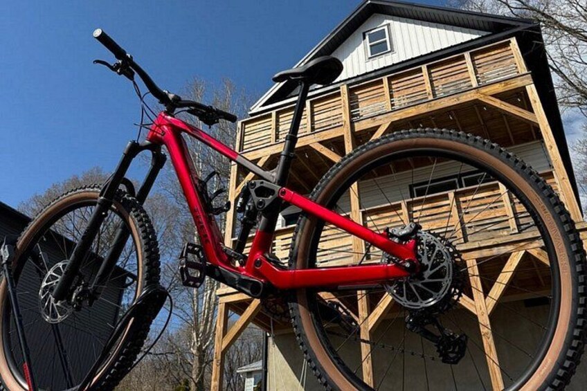 A red mountain bike leaning against a wooden structure. 2