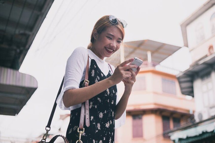 A person using a smartphone outdoors, with buildings in the background. 4