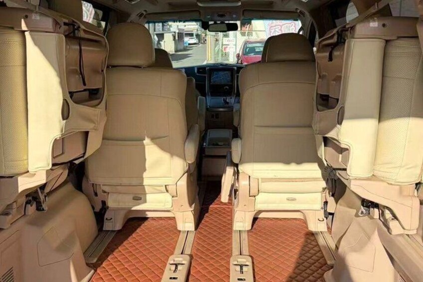 A vehicle interior with beige leather seats, a central console, and a patterned floor mat. 4