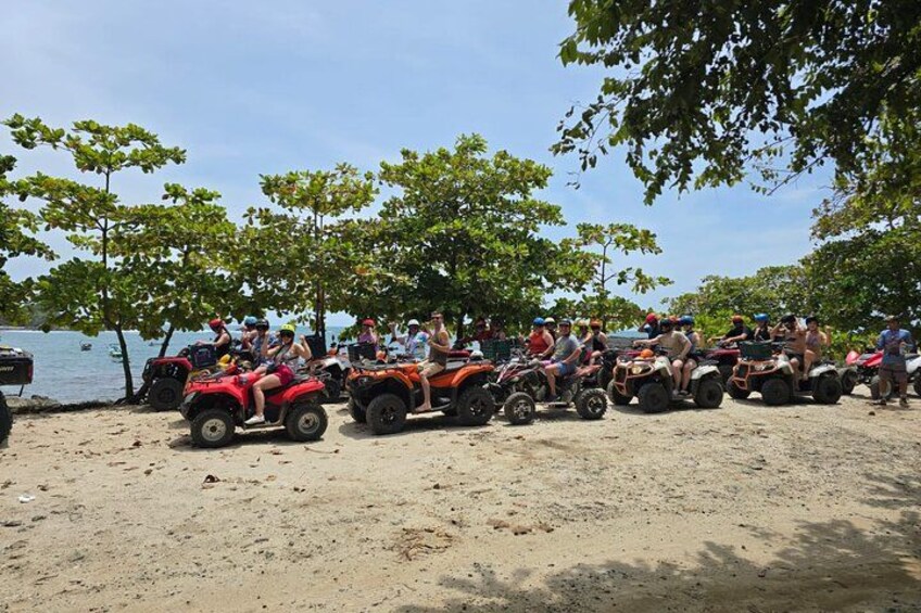A group of people on ATVs near a body of water with trees in the background. 3