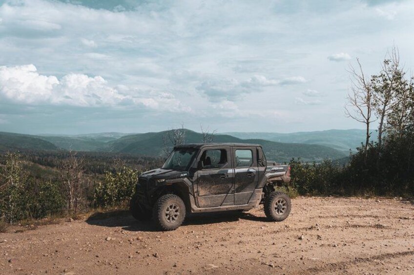 A black off-road vehicle parked on a dirt road with a mountainous landscape in the background. 3