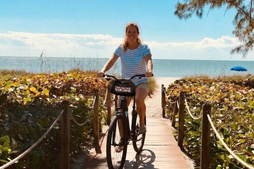 A person riding a bicycle on a wooden boardwalk by the sea. 5