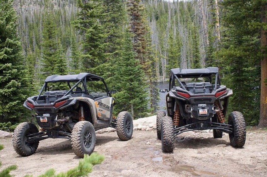 Two off-road vehicles on a dirt trail in a forested area. 2