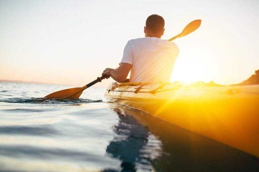 A person kayaking on calm water during sunset. 2