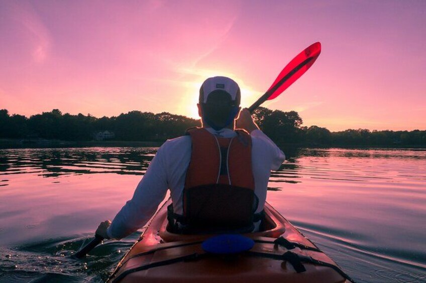 A person kayaking on a calm body of water during sunset. 3