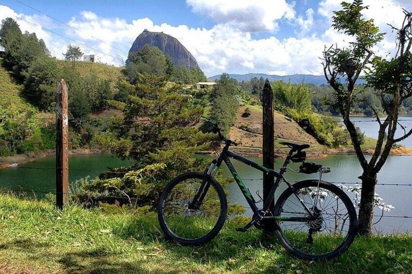 A bicycle parked by a lake with a mountain in the background. 2