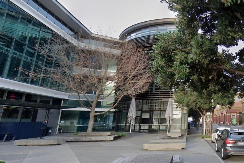 A modern building with glass windows, a tree, and a car parked on the street. 5