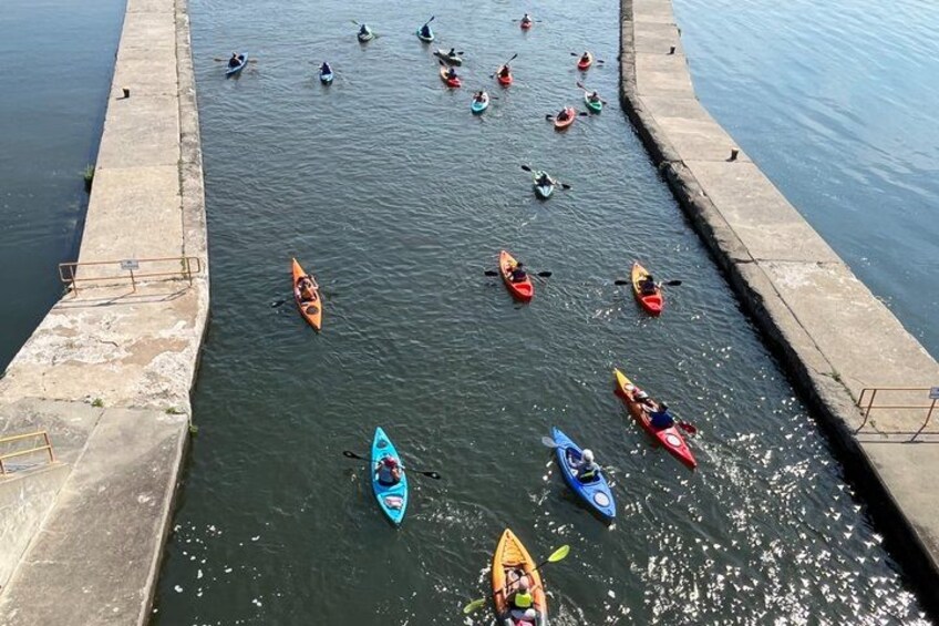 A group of kayakers on a calm body of water near a concrete dock. 3