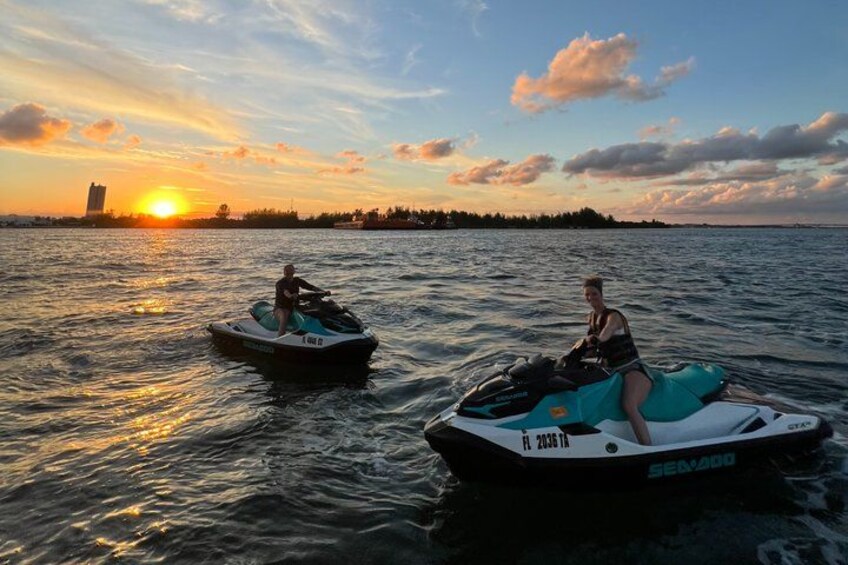 Two jet skis on calm water with a sunset in the background. 3