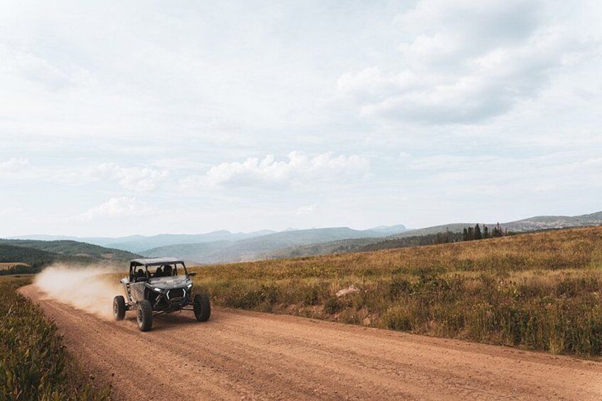 A vehicle driving on a dirt road in a hilly landscape. 2