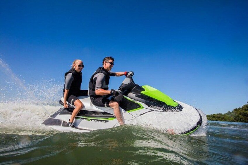 Two people on a jet ski, water splashing around them. 3