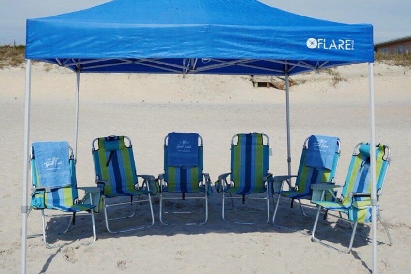 A beach with a blue canopy labeled 'FLARE' and five beach chairs. 3