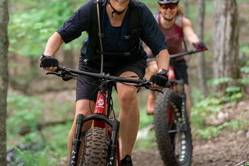 Two mountain bikers on a trail surrounded by trees. 5