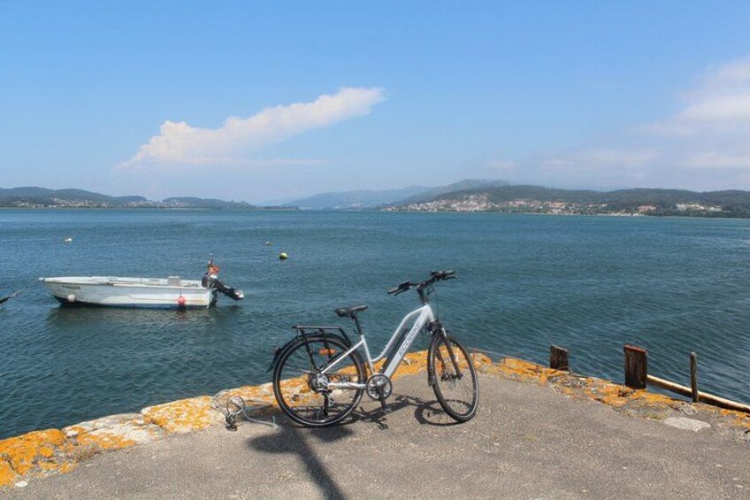 A bicycle parked by a waterfront with a boat in the background. 2
