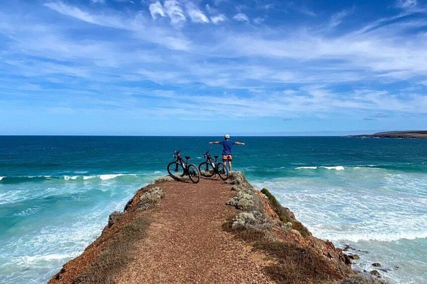 A coastal path with bicycles and a person standing at the end. 1