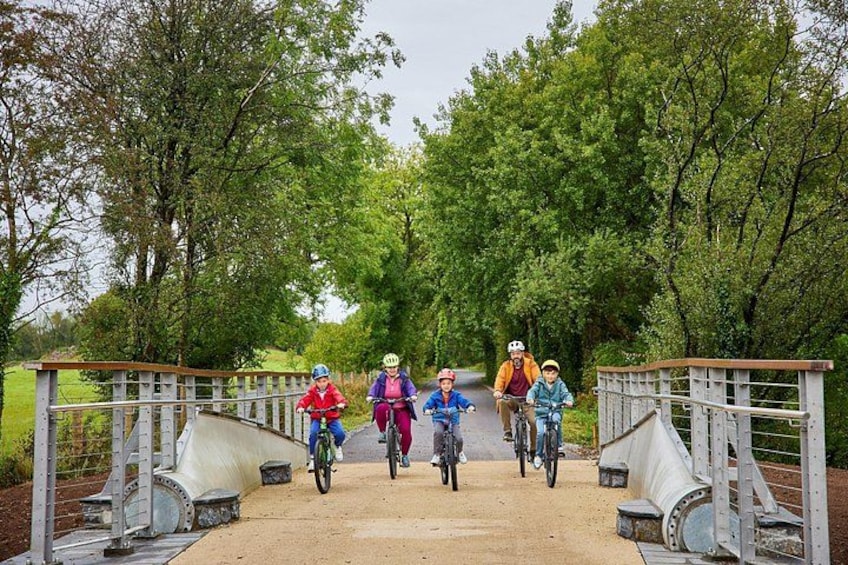 A group of cyclists on a dirt path surrounded by trees. 1