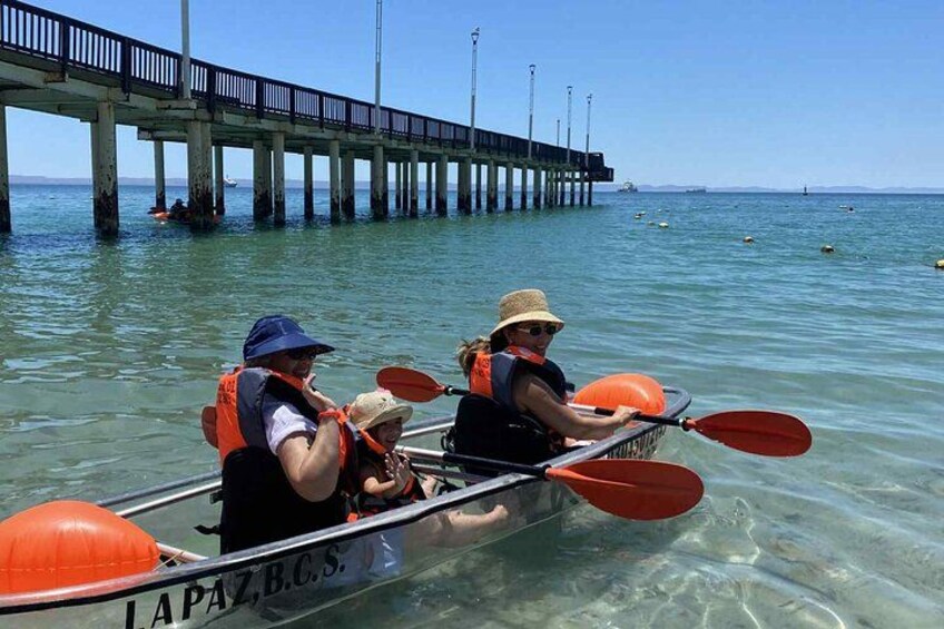 Two people kayaking on a clear day with a pier in the background. 3