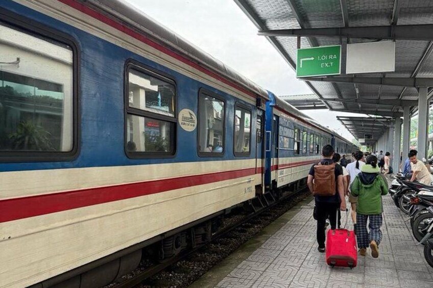 A train station platform with a train, passengers, and a sign indicating an exit. 1