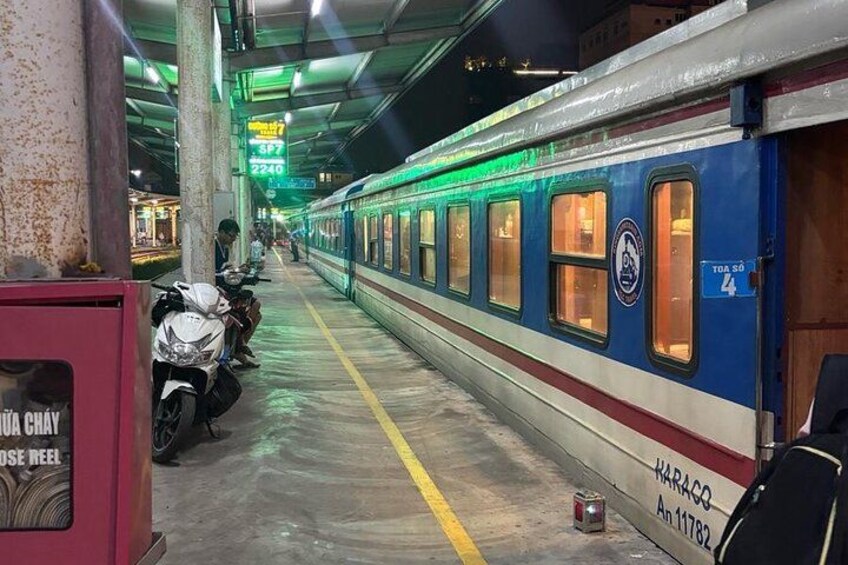 A train station platform with a train, a motorcycle, and a sign. 3