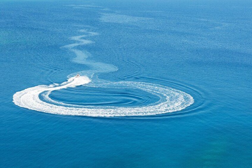 A boat creating a circular wake pattern in the ocean. 4