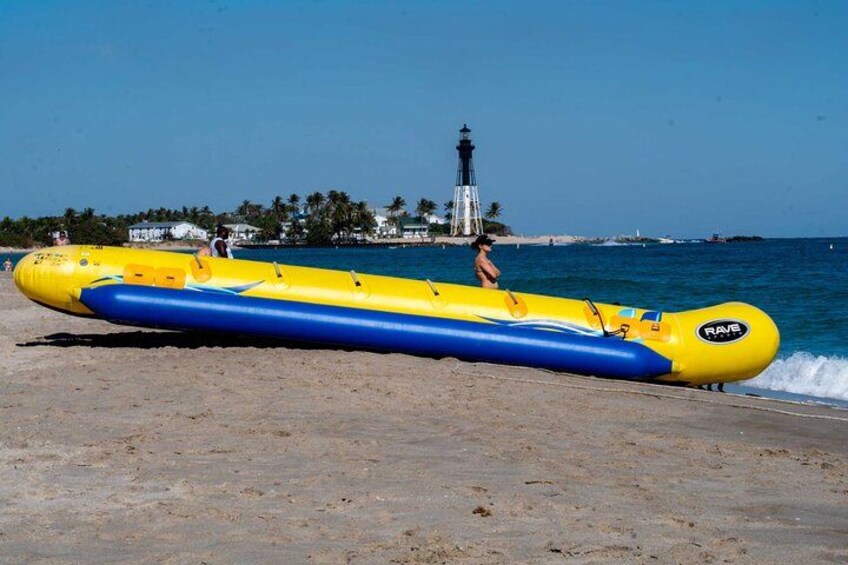 A yellow and blue inflatable raft on a beach with a lighthouse in the background. 1