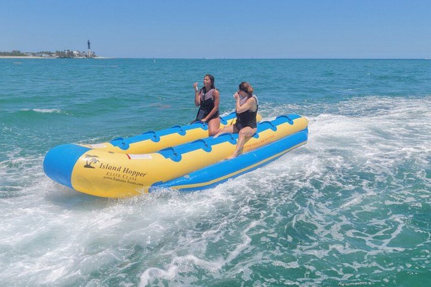 Two people on a blue and yellow inflatable raft moving through turquoise water. 3