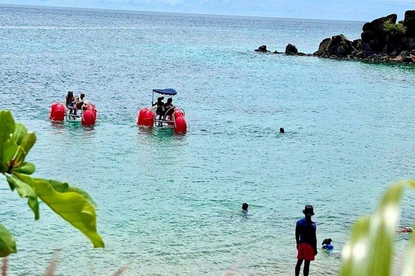 People on paddle boats in a calm sea, with rocky outcrops in the background. 2