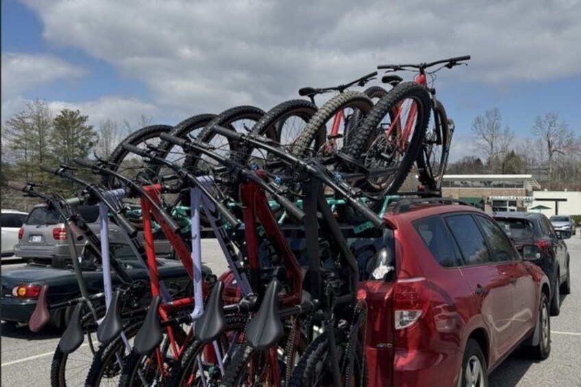 A parking lot with multiple bicycles mounted on a rack attached to a red car. 4