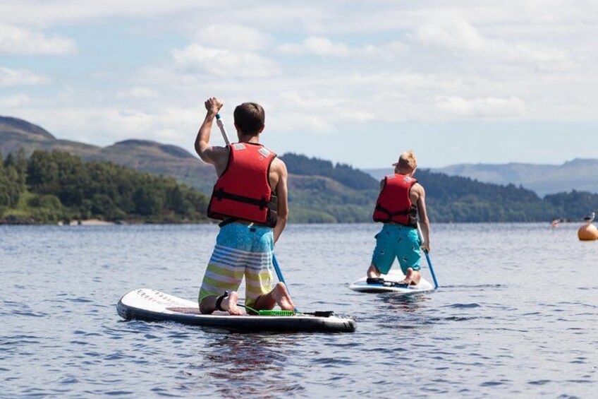 Two people paddleboarding on a calm lake with mountains in the background. 5