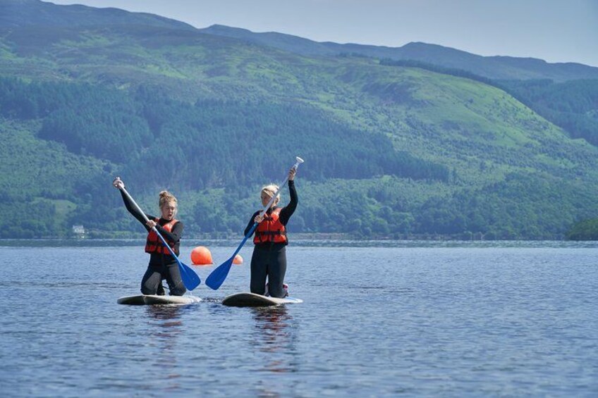 Two people kayaking on a calm lake with green hills in the background. 4