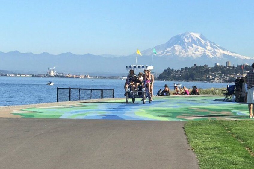 A beach with a colorful mural, a mountain in the background, and a few people. 1