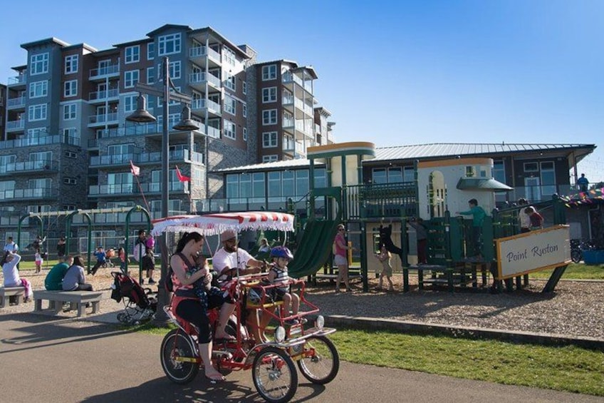 A playground with a sign reading 'Point Ruston,' a bicycle with a basket, and a building in the background. 2