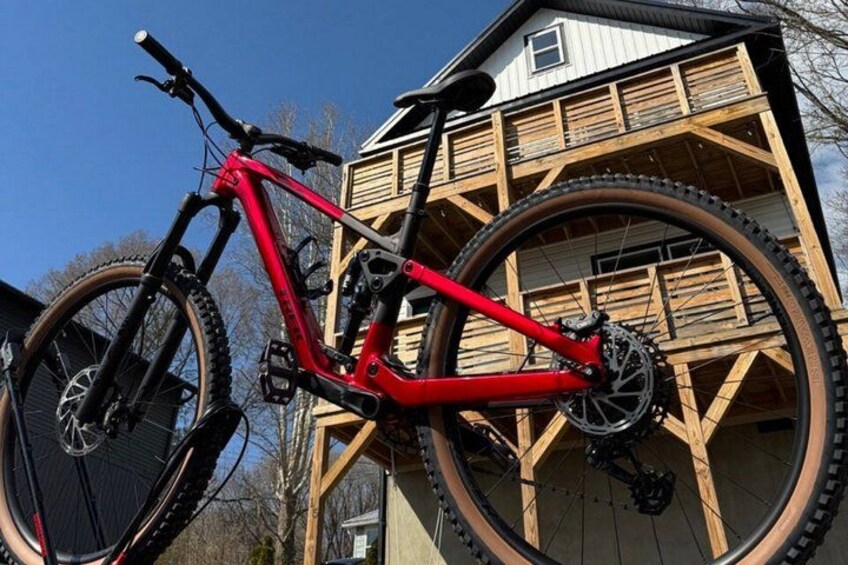 A red mountain bike parked in front of a wooden building with large wheels. 5