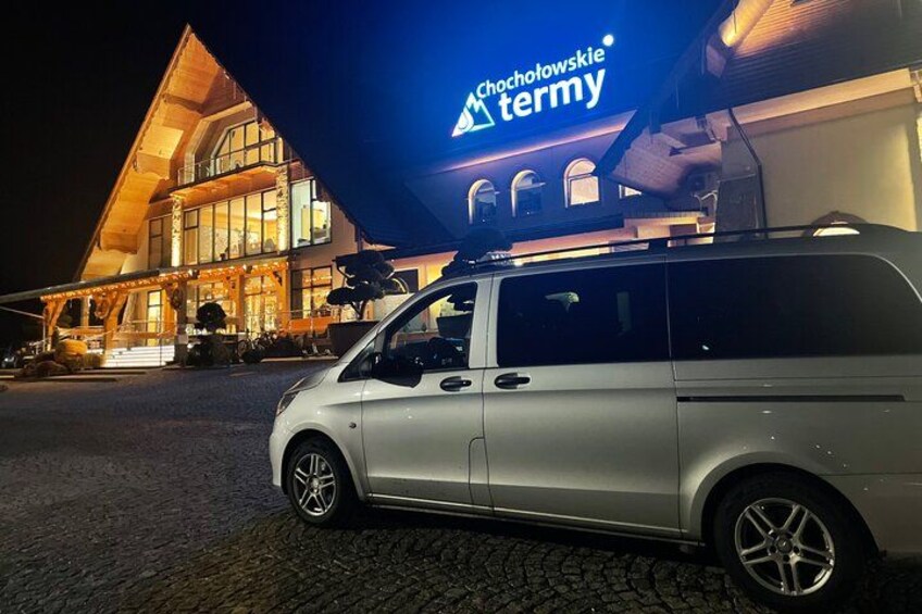 A white van parked in front of a building with a sign that reads 'Chocotowskie termy'. 2
