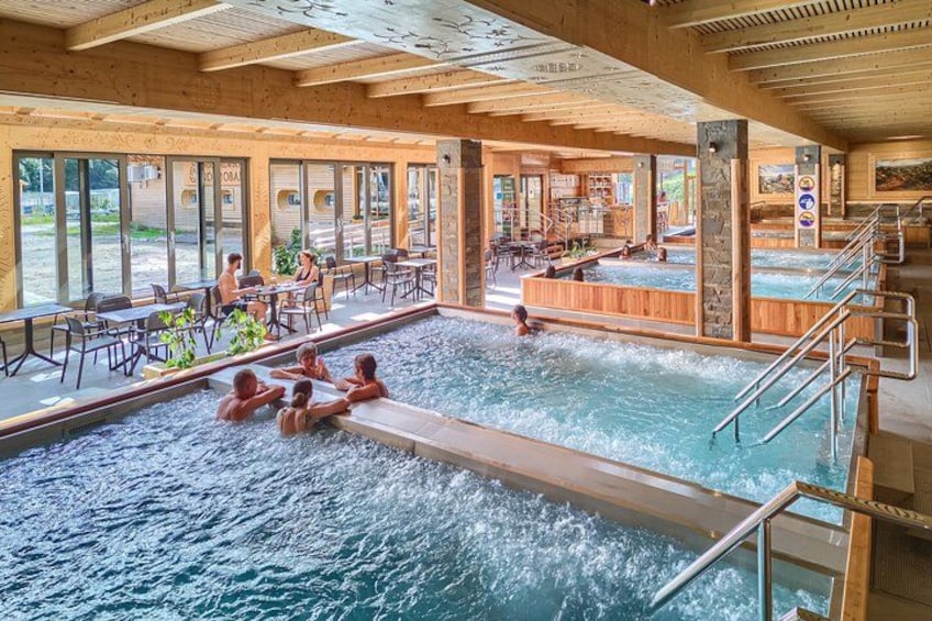 An indoor swimming pool with wooden beams, a seating area, and a sauna. 5