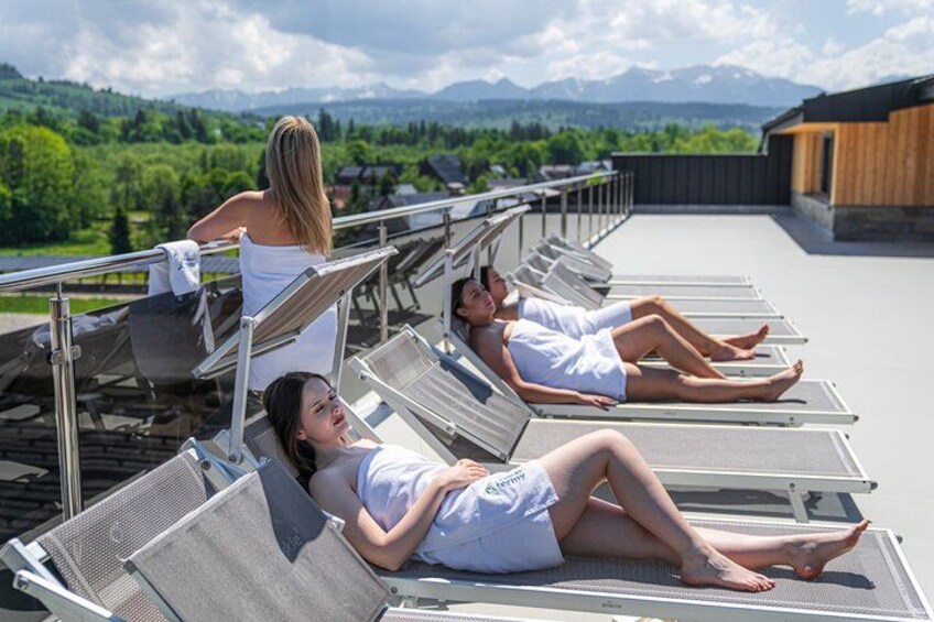 A rooftop lounge with sun loungers overlooking a mountainous landscape. 4
