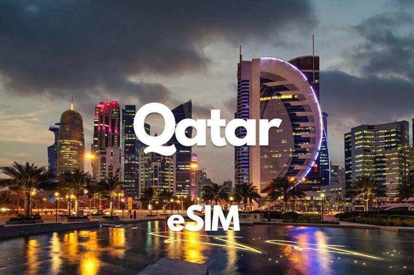 A cityscape at dusk with illuminated buildings and a large circular structure reflecting on water. 1